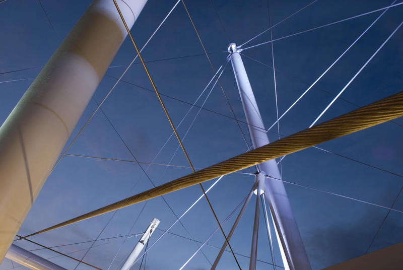 Architectural steel with a network of poles, stays and cables against a blue sunny sky