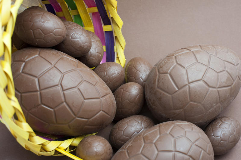 Assorted sized chocolate Easter eggs spilling out of a decorative wicker basket