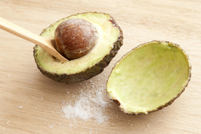 Close-up of cut avocado with seed and salt on wooden table