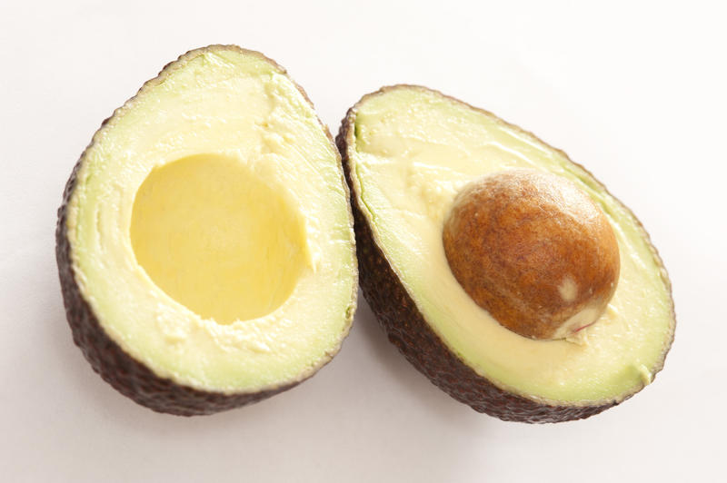 Avocado fruit sliced open to reveal the tasty flesh and large pip for a delicious salad ingredient in vegetarian and vegan cuisine