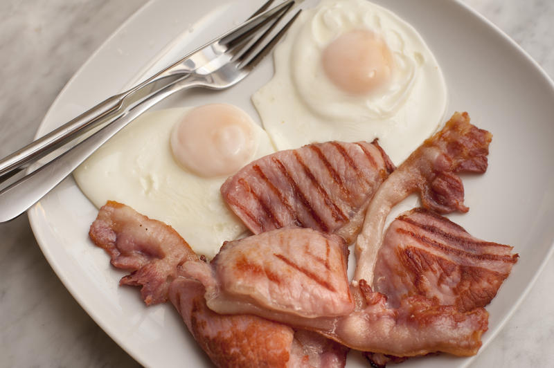 View from above of a hearty breakfast serving of rashers of grilled bacon and two fried eggs