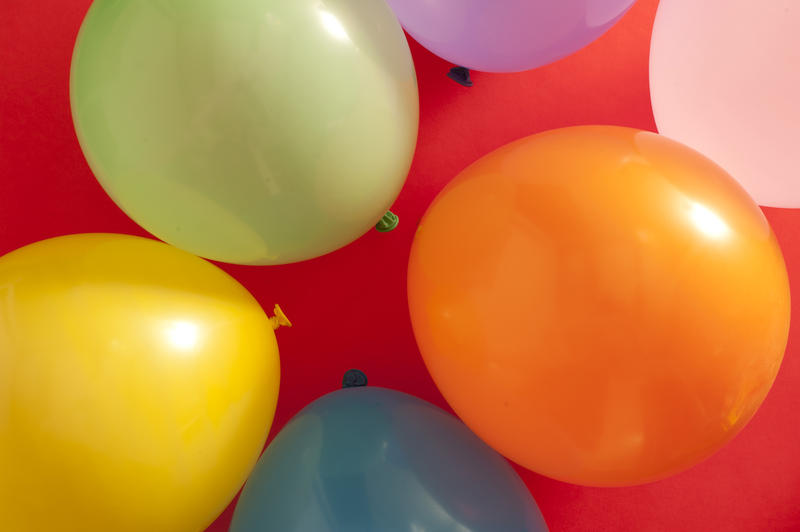 Full frame overhead background of colorful party balloons on red for a festive theme