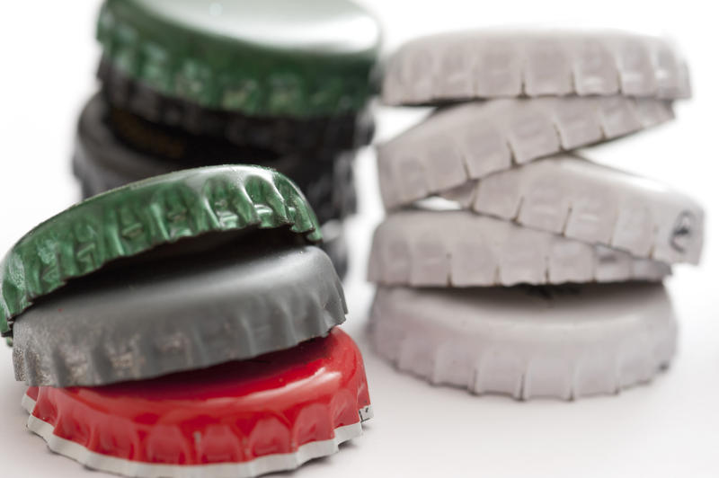 Stacks of used beer bottle tops in red, green and white conceptual of a party, close up view on white