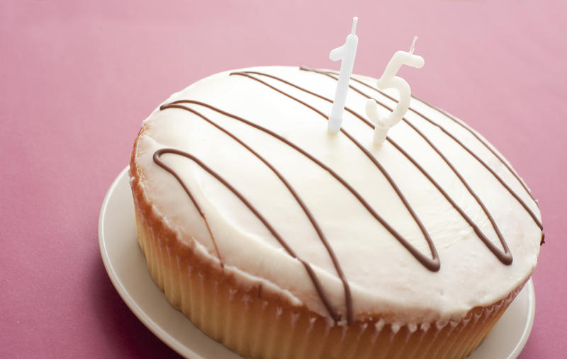 Iced fifteenth birthday cake with two unlit number 15 candles in the centre to celebrate the birthday of a teenager