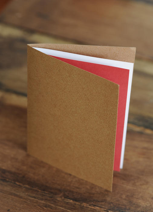 A blank greeting card in unbleached paper on a wooden surface