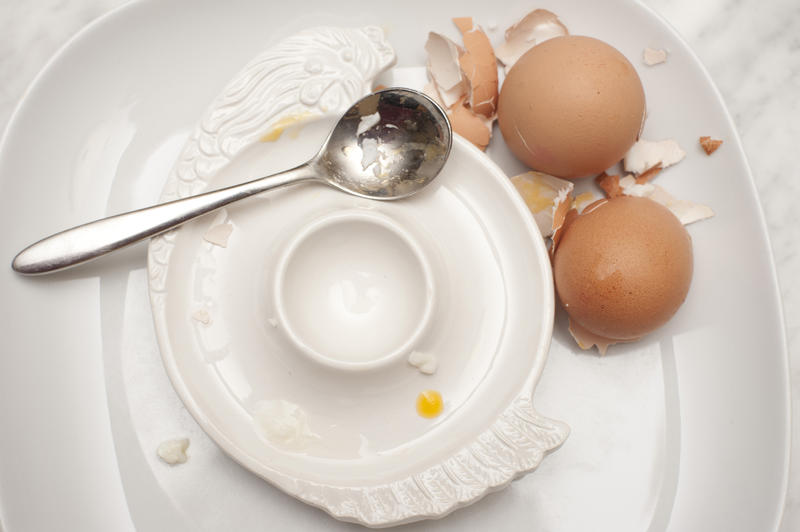 View from above of an empty egg cup with two overturned eggshells from two boiled eggs that have been consumed for breakfast