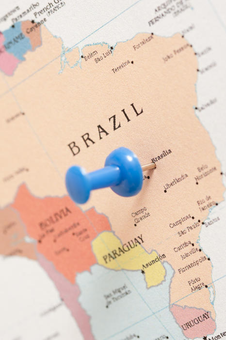 Blue plastic thumb tack pin inserted in a map of Brazil, conceptual of travel destinations and planning a summer vacation