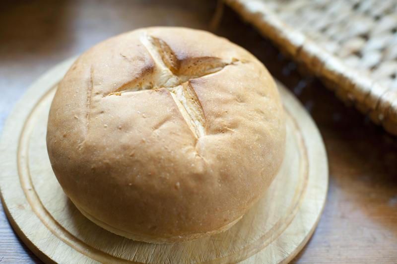 Freshly baked traditional round crusty cob roll on a board to eat as an accompaniment to a meal , close up high angle view
