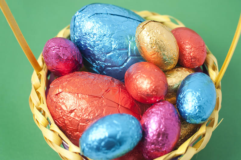 Overhead view of a basket filled with brightly coloured Easter Eggs in various sizes