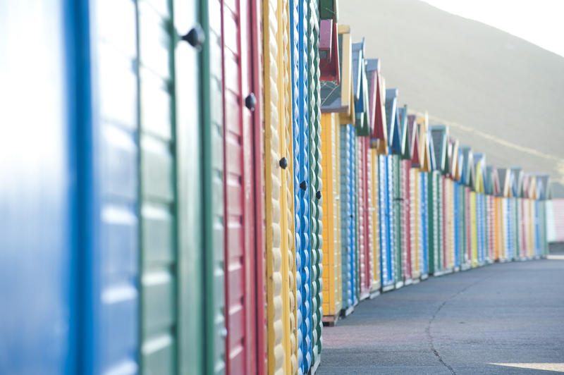 Receding row of brightly coloured cabins or beach huts on Whitby West Cliff for the convenience of bathers and holidaymakers