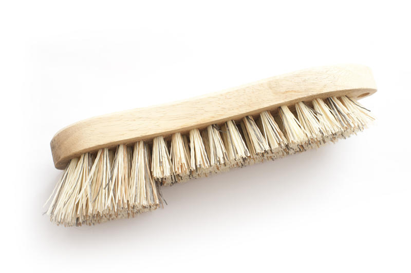 Wooden household scrubbing brush with double length bristles on a white background with copyspace