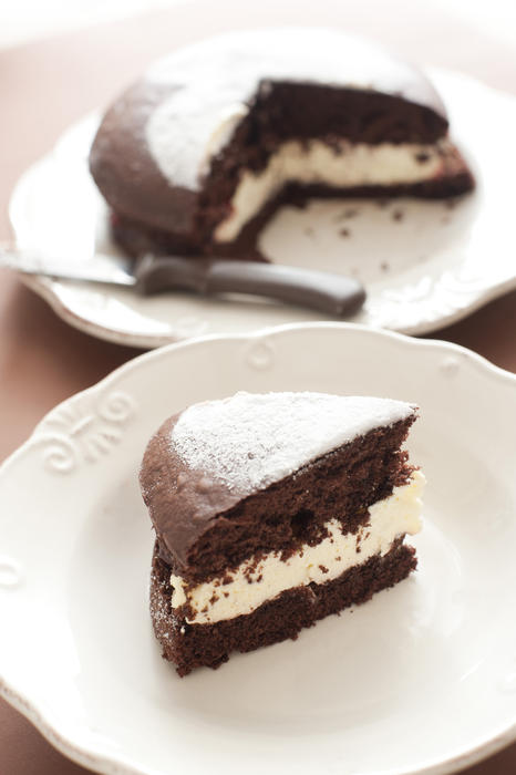 Slice of delicious freshly baked chocolate cake filled with cream or buttercream and served on a plate for dessert