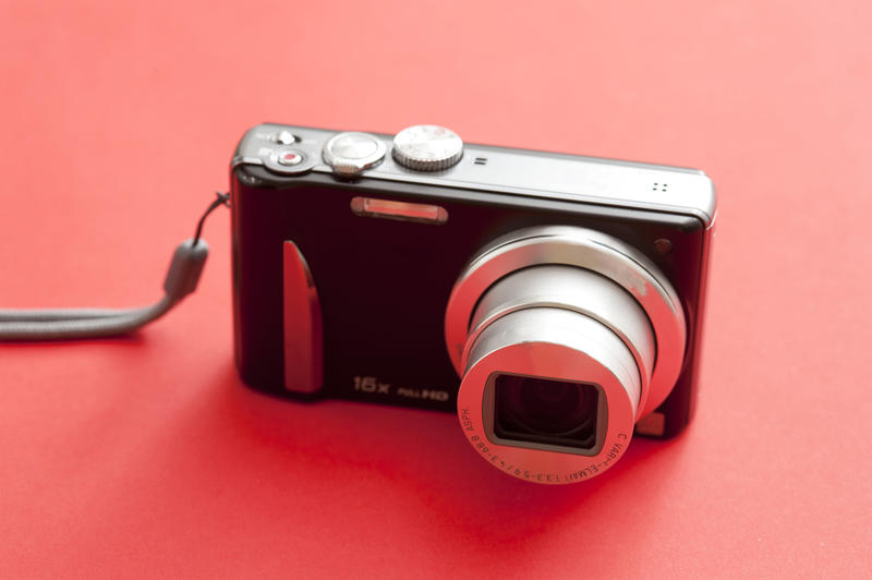Close up Standing Black and Silver Digital Camera Isolated on Red Background