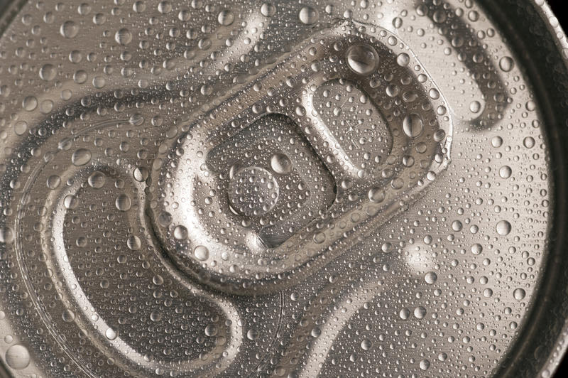 Top of a chilled beverage can with condensed moisture and the pull tab, unopened, close up top view