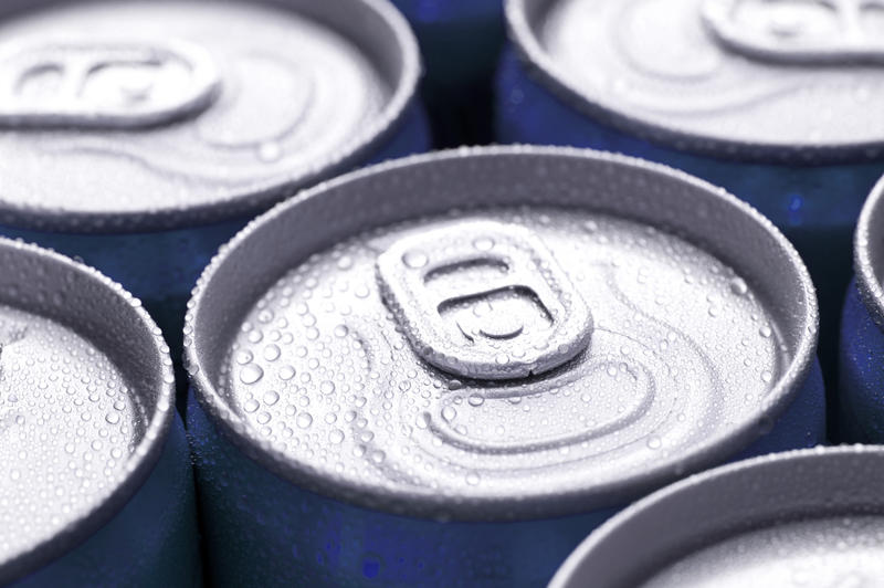 Canned drinks background wth a close up low angle view of the tops of the tins and pull tabs with water condensation from the cold