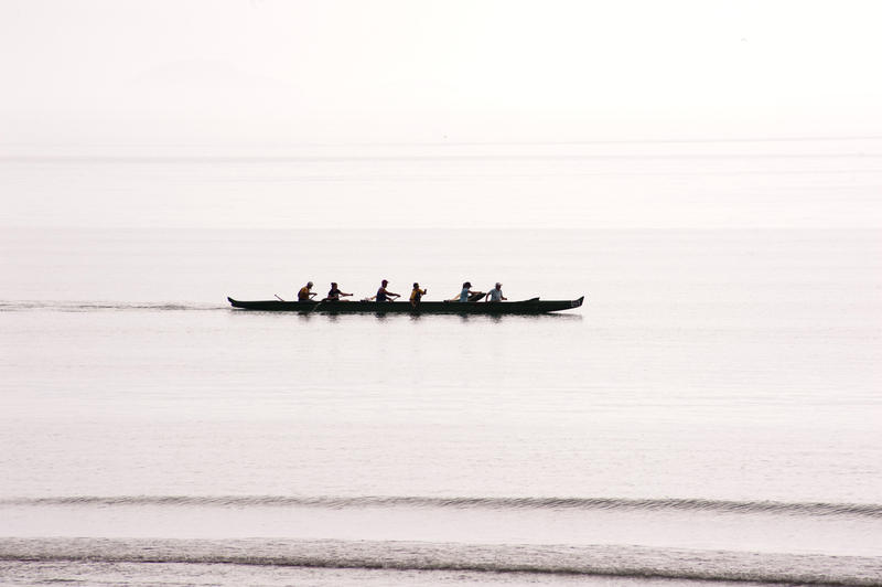Silhouette of a team of rowers in a canoe practicing and training for a race on bright calm water