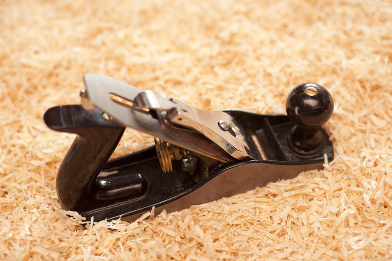 Manual woodworking plane with an adjustable blade standing on a bed of fresh wood shavings with copyspace in a DIY and renovation concept