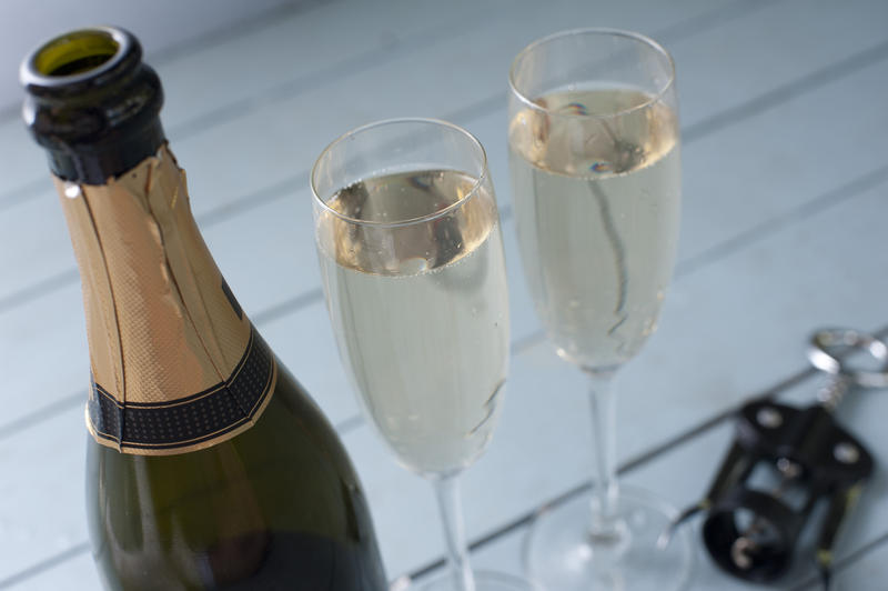 Close up of the neck and gold label on a champagne bottle with two full flutes behind for a romantic occasion or festive celebration