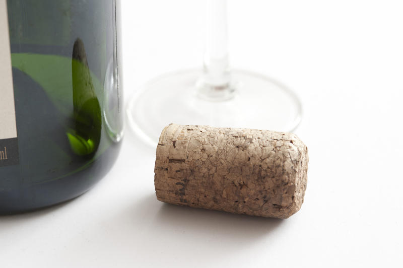 Close Up Still Life of Cork on White Background Beside Green Glass Champagne or Wine Bottle and Wine Glass