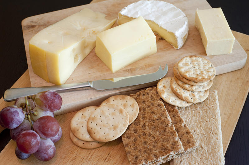 Variety of cheeses on a cheeseboard served as an appetizer with wheat crackers or crispbread and water biscuits