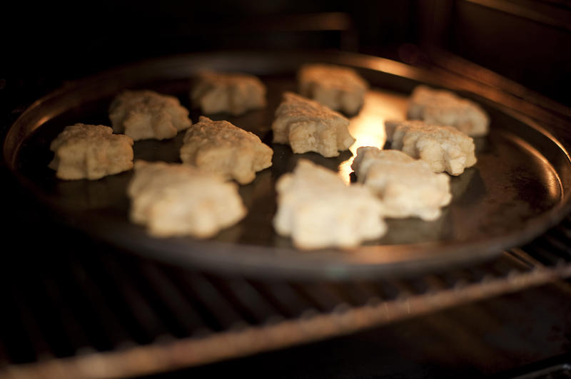 Christmas cookies in the shape of Christmas trees baking inside an oven on a baking tray