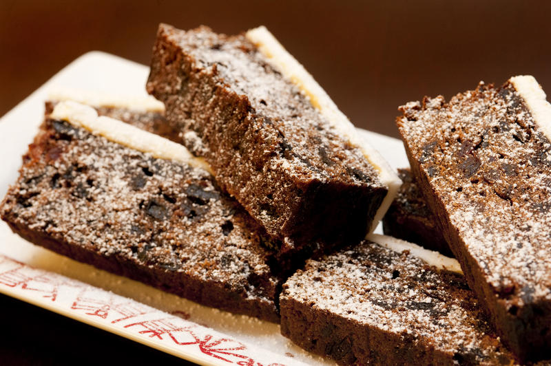 Plate of sliced traditional Christmas fruit cake to celebrate the festive season, closeup view showing marzipan icing and raisins