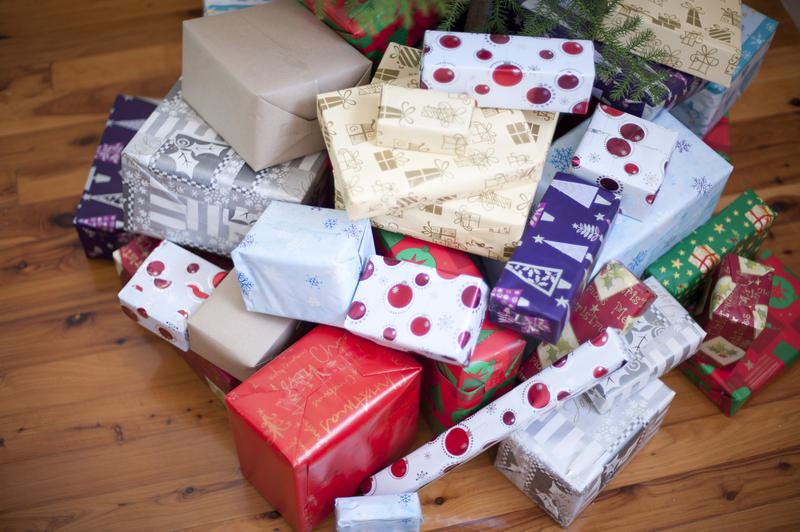 High angle view of a large pile of pretty colourful Christmas gifts in a variety of patterned gift wrap on a hardwood floor in a home