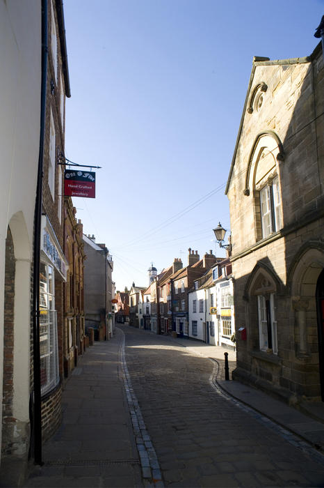 View of the winding narrow cobbled street known as Church Street in Whitby which leads from the town centre to the bottom of the 199 steps leading up to St Mary's Church on Tate Hill