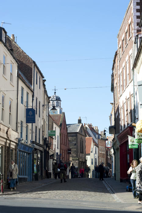 Tourists in paved medieval street with church in a distance view