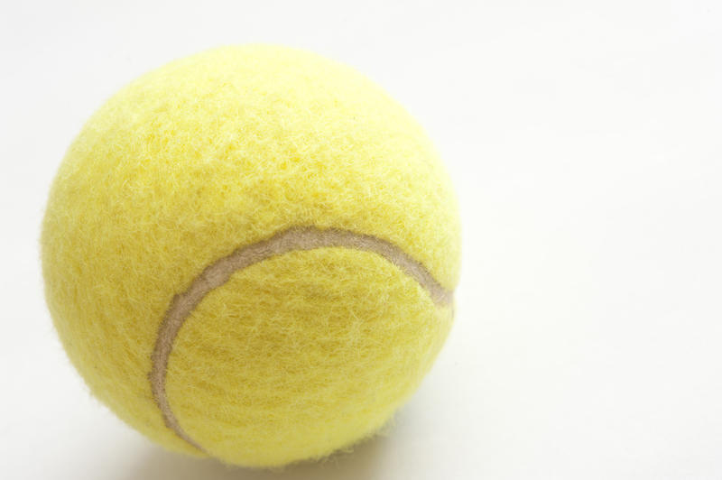 Close up of a yellow tennis ball on white with copyspace in a sport and fitness concept