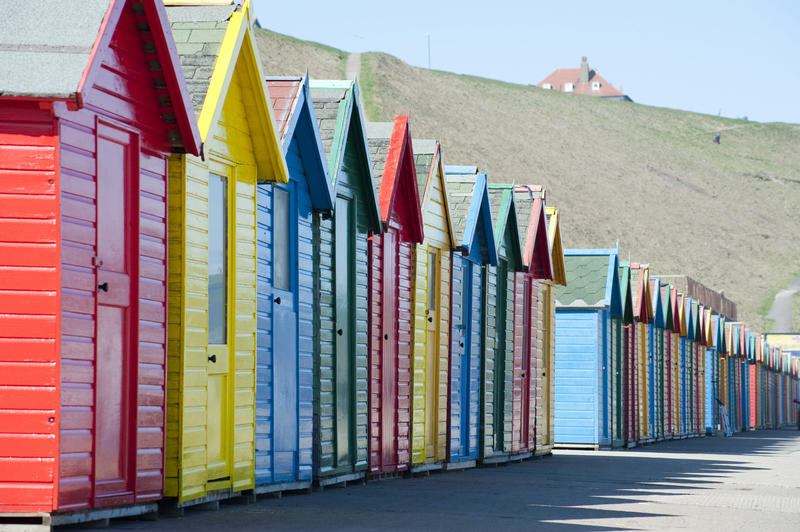 Row of colourful wooden Beach huts at Whitby sands on the West cliff or headland