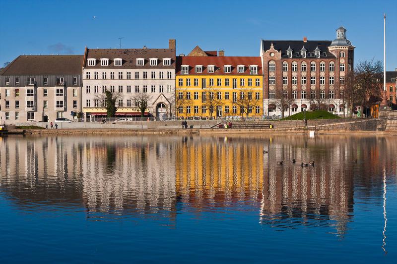 <p>Row of Colorful Buildings on Sunny Day Reflected in Water</p>