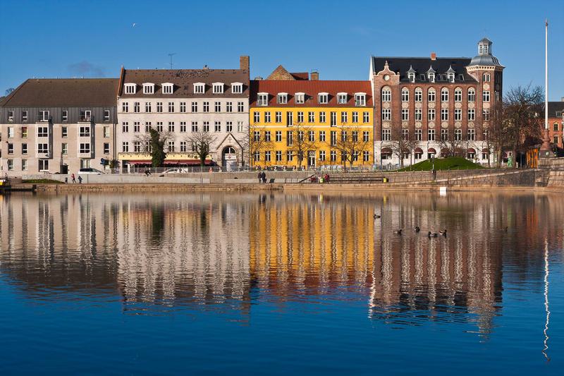 <p>Row of Colorful Buildings on Sunny Day Reflected in Water</p>
