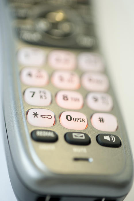 Telephone handset viewed low angle from the end with shallow dof and focus to the open and message buttons or functions