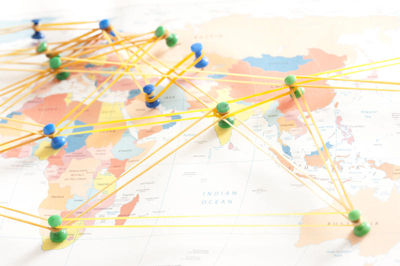 International network concept with colorful drawing pins or thumb tacks on a global map connected by rubber bands