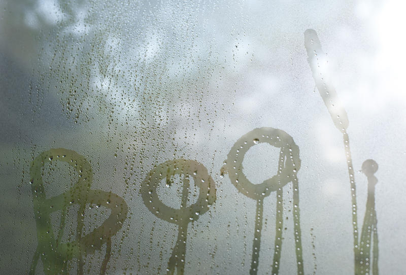 Boo - in dripping letters on cold condensation on window glass bathed in a ghostly white light as a backdrop for a Halloween greeting card or invitation