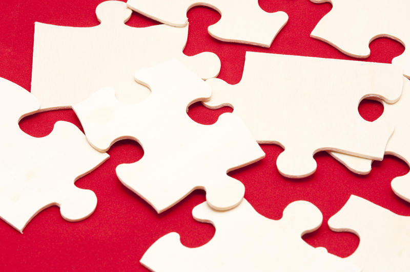 Scattered white jigsaw puzzle pieces on a colorful red background in a concept of problem solving
