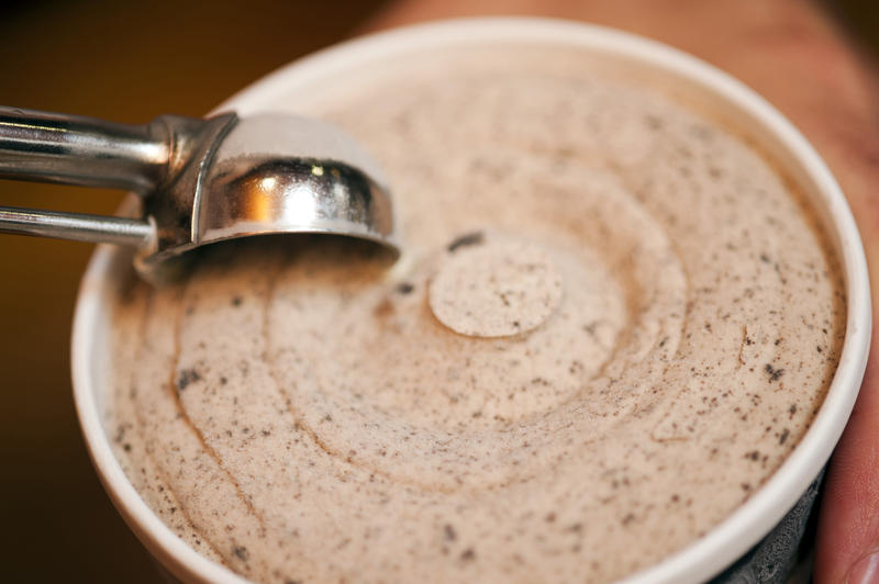 Serving up tasty creamy cookie ice cream from a bowl using a stainless steel scoop, close up high angle view