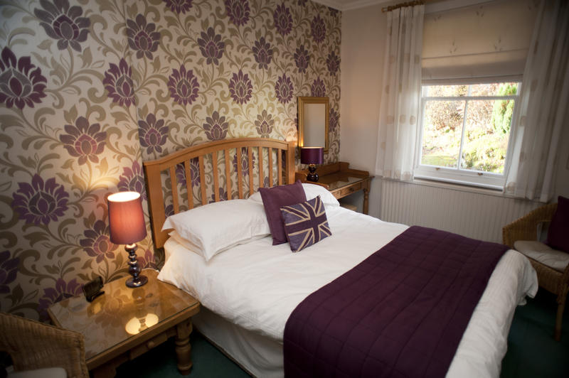 Cosy old-fashioned bedroom with a wooden framed double bed and illuminated lamps on bedside tables in an interior decor concept