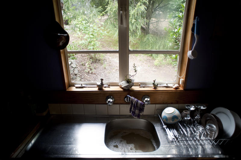 Cottage kitchen with a garden view and a small stainless steel sink unit below the window with washing up draining on the side