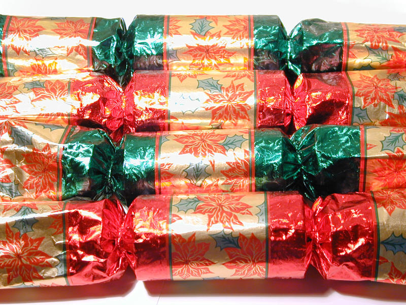 Colorful festive Christmas table crackers with gold foil patterned with poinsettia flowers arranged in a receding row of alternating red and green