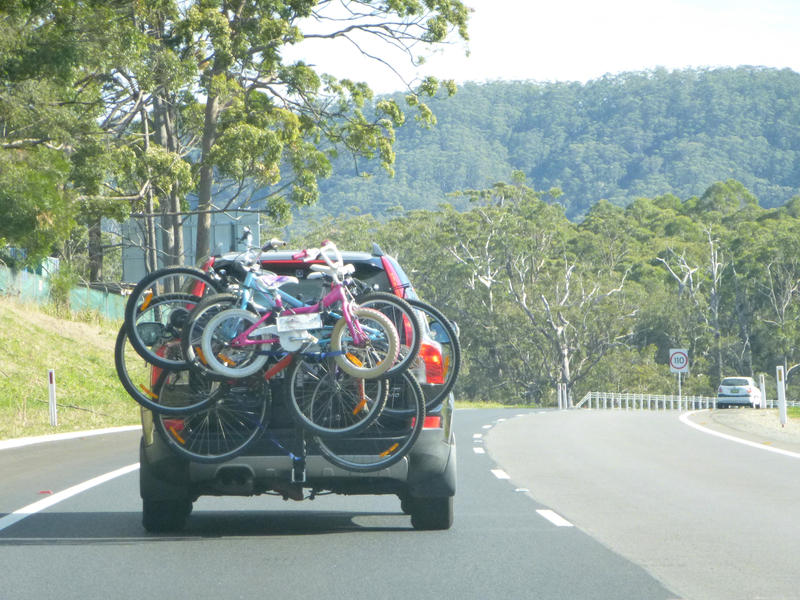 Vehicle driving on a road with a cycle carrier on the back with an assortment of family bicycles of different sizes for an active weekend