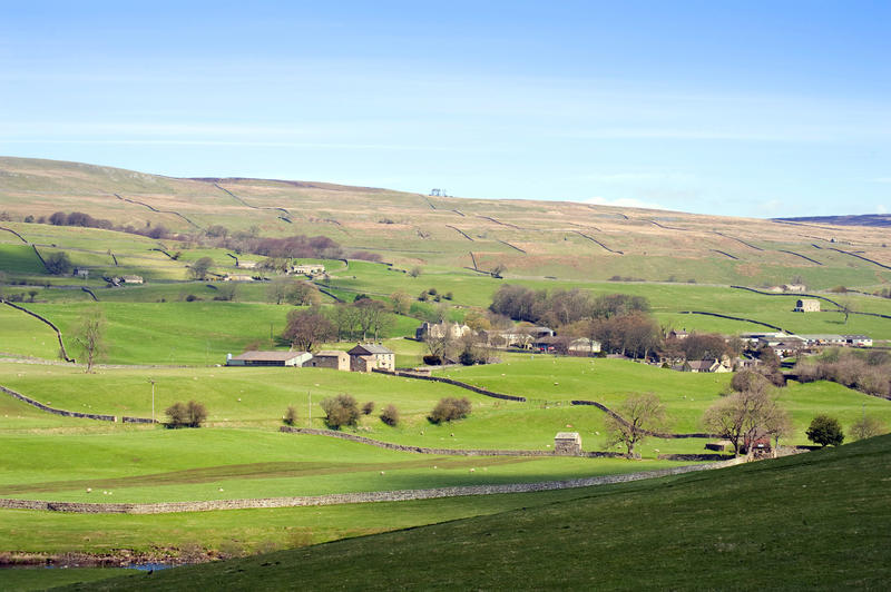 View across gently rolling hills and remote farm buildings in the scenic Yorkshire Dales, England