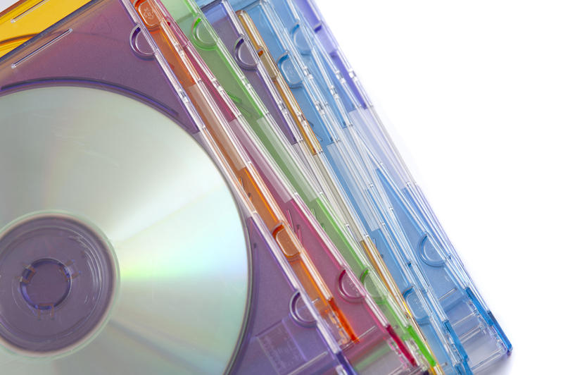 Stack of Compact Discs in Colorful Jewel Cases as seen from Above on White Background