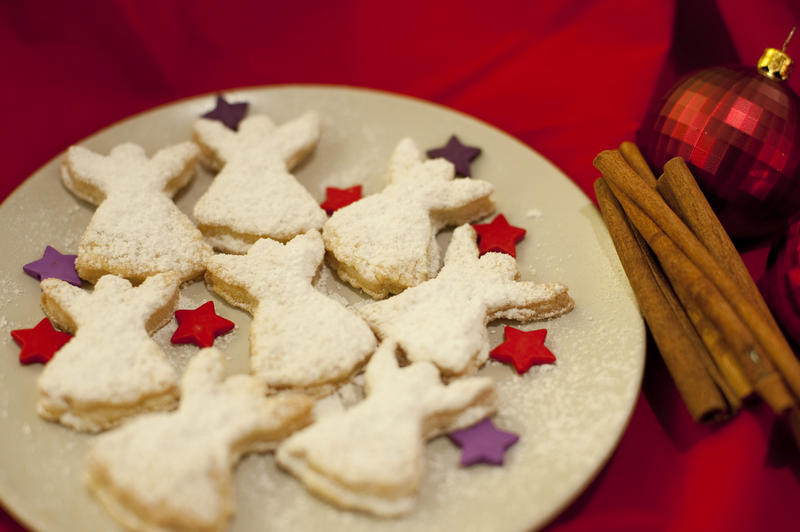 Fresh home baked angel Christmas cookies arranged with colourful stars on a plate on a festive Christmas table