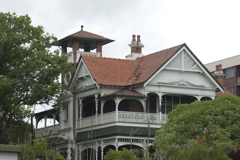 Old derelict abandoned Victorian style double storey house with covered balconies nestling in trees