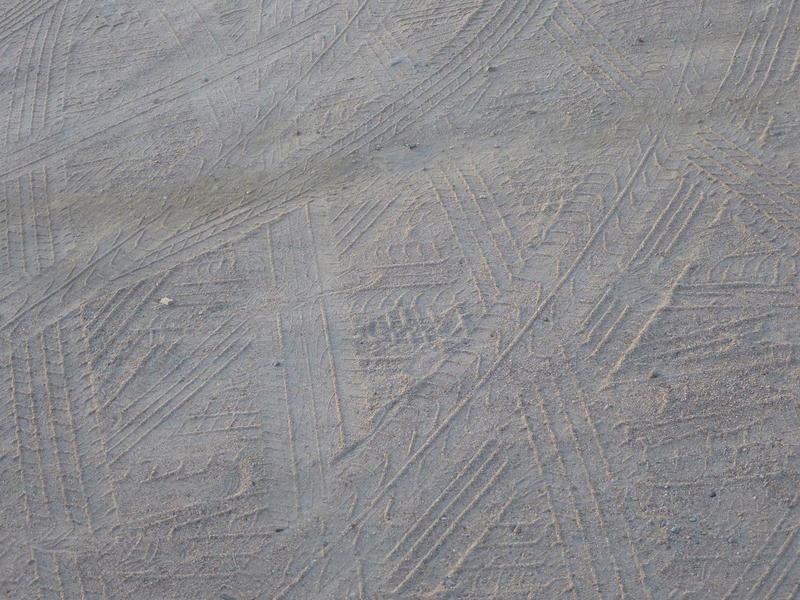 Tyre tread marks in the sand of a dirt track left by vehicles that have driven by, full frame background texture and pattern