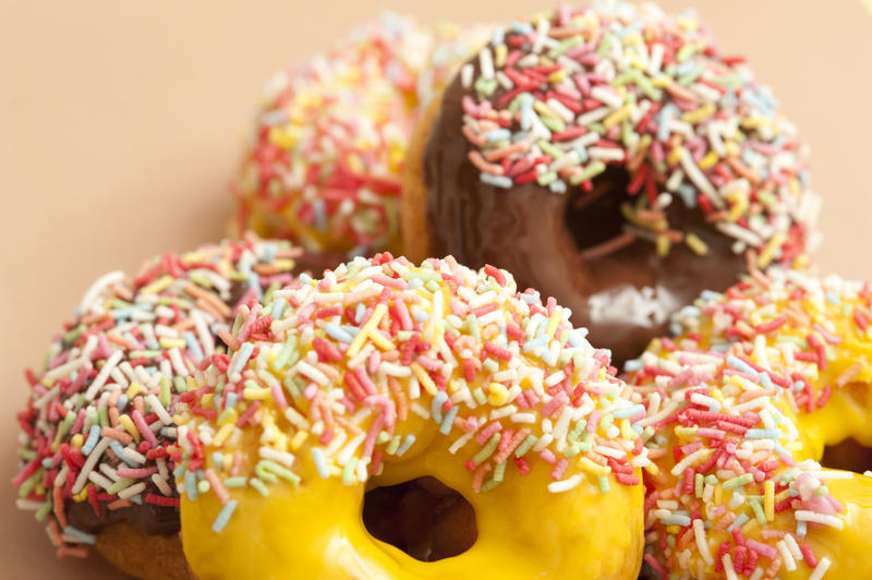 Doughnut assortment with colorful ring donuts glazed with chocolate, lemon and orange icing covered in multicolored candy sprinkles