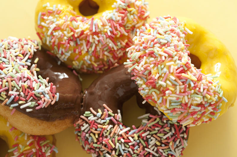 Close up view of delicious fresh glazed doughnuts with colorful sprinkles for breakfast or teatime
