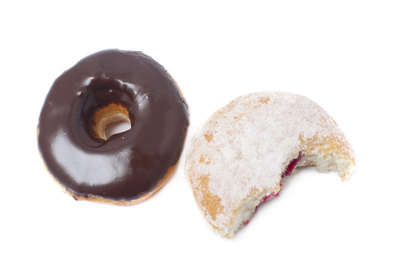 Freshly baked fried chocolate and jam doughnuts on a white background with the jam doughnut broken open to show the filling